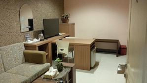 A compact living space with a sofa, a small dining table, a TV, and a cabinet. - Patria Palace Hotel (Blitar)