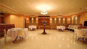 A spacious hotel lobby with multiple round tables and chairs, a central decorative table, and a reception area with a sign. - Patria Palace Hotel (Blitar)