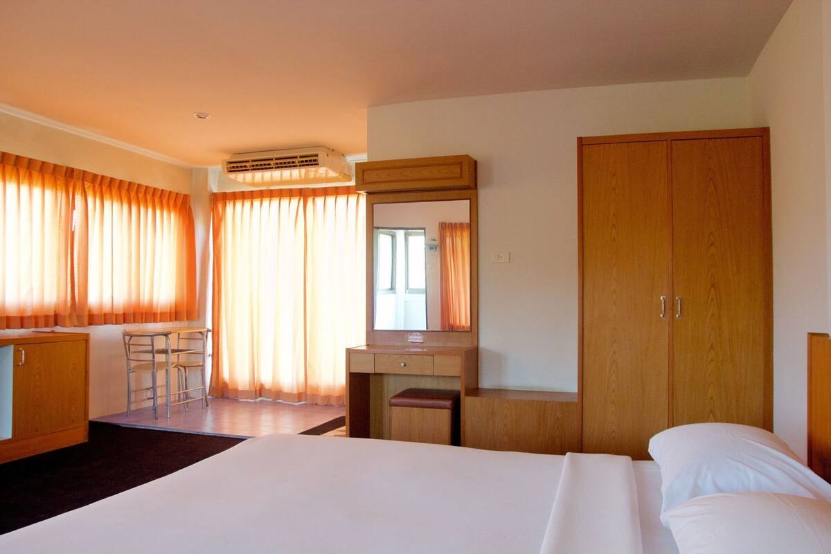 Une chambre d’hôtel comprenant un lit, un bureau, une chaise, une armoire et un miroir.