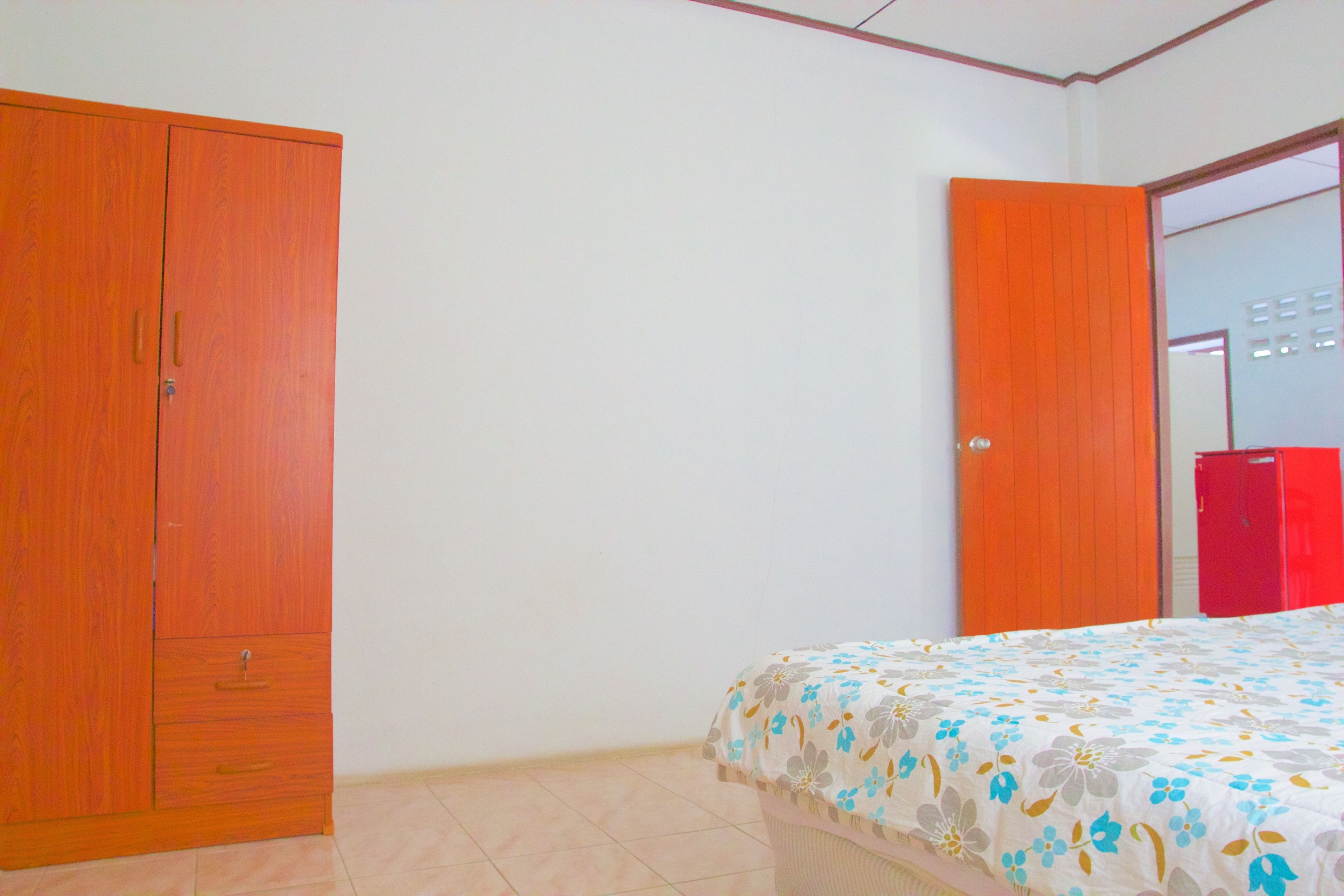 A bedroom with a bed, a wardrobe, and a door leading to another room.