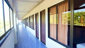 A corridor with large windows, doors, and a blue-tiled floor.