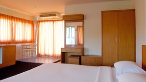 A hotel room with a bed, a desk, a chair, a wardrobe, and a mirror.