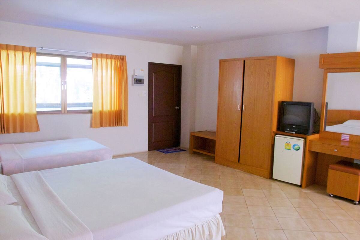 Une chambre d’hôtel avec deux lits, une télévision, une armoire et un petit réfrigérateur.