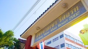 A sign for 'Sichang Shine Resort 2002' with a clear view of the building's architecture and a flag.