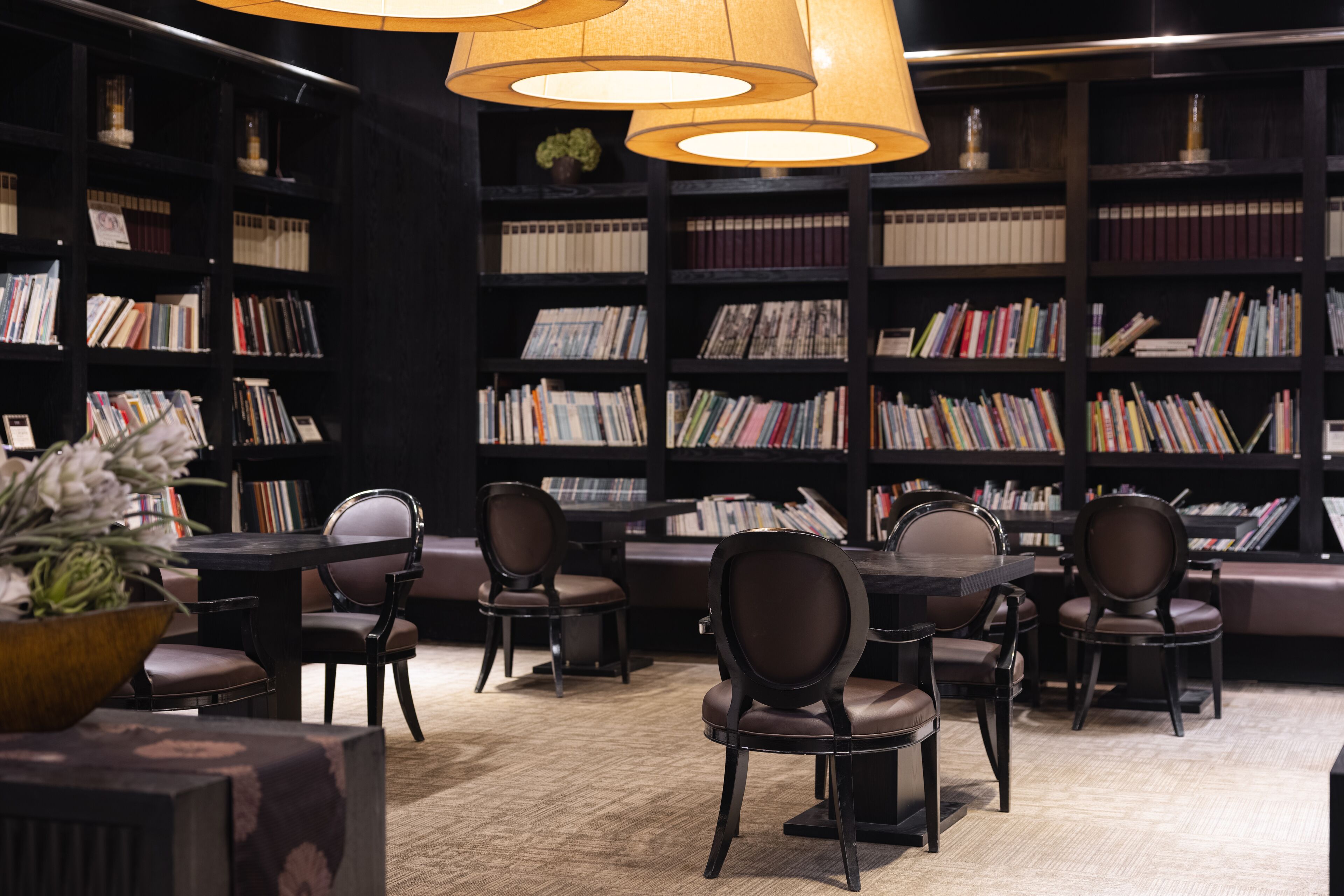 Uma biblioteca com estantes, poltronas de couro e uma mesa.