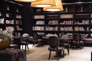 Une bibliothèque avec des étagères, des fauteuils en cuir et une table.