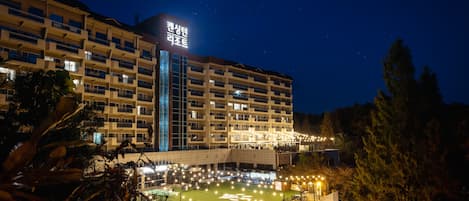 Un hôtel à plusieurs étages, doté d’une façade bien éclairée et d’une cour intérieure.