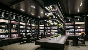 Une bibliothèque moderne dotée de nombreuses étagères, d’espaces de lecture et de plantes décoratives.