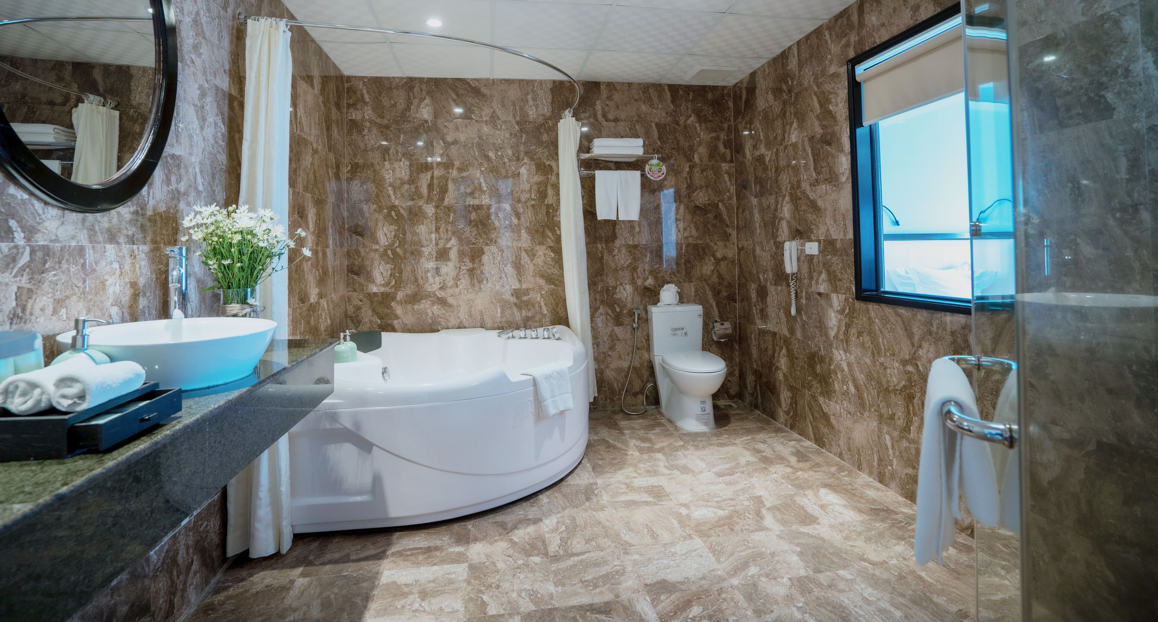 A modern bathroom with a large bathtub, a round sink, and a toilet.