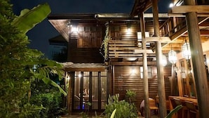Un bâtiment en bois doté d’un espace extérieur abrité avec des sièges et d’un escalier menant à un niveau supérieur.