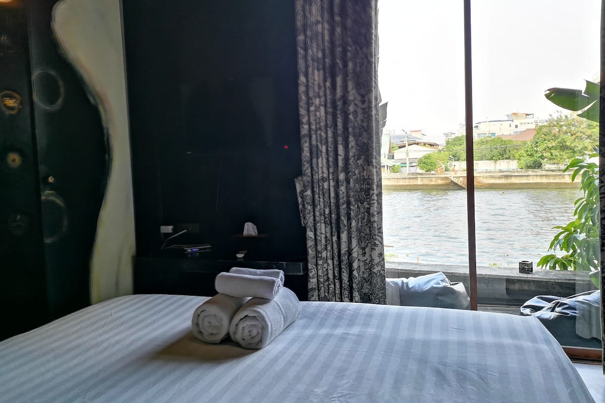 Een hotelkamer met een bed, een televisie en uitzicht op een rivier en gebouwen.