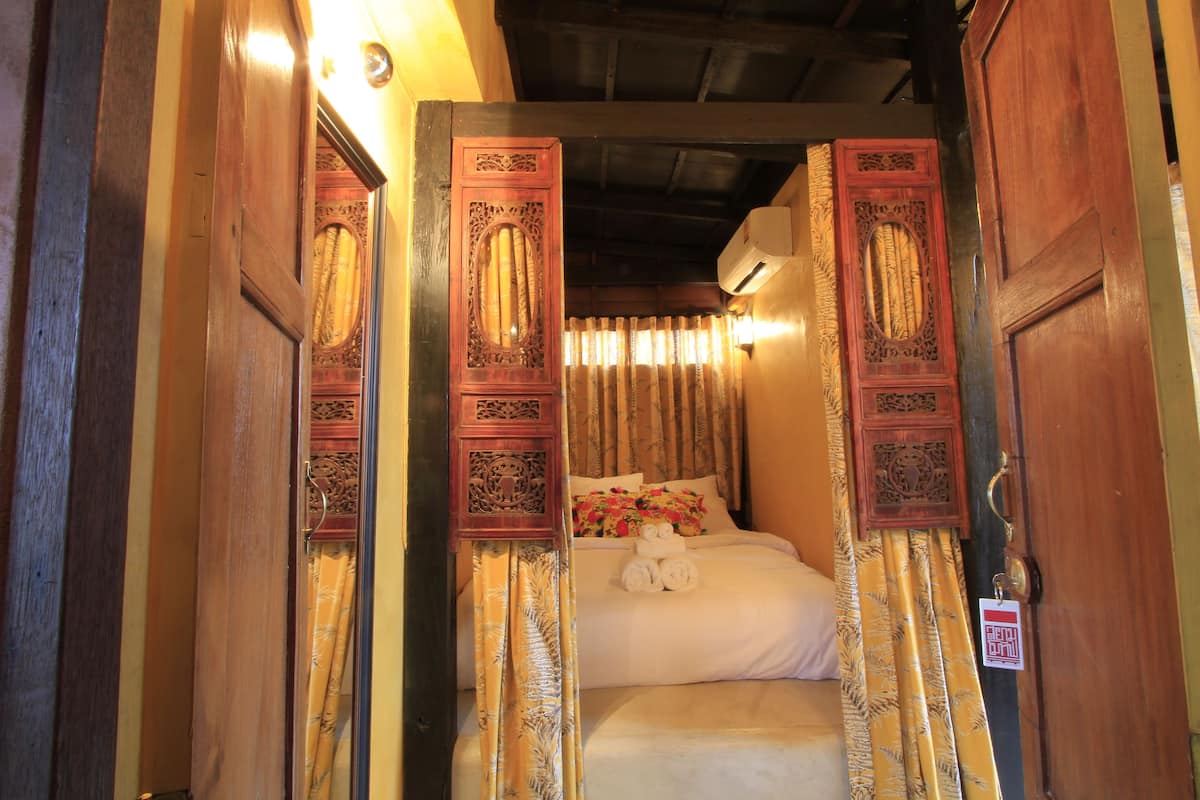 Een klassieke kamer met een bed, gordijnen en een houten deur met gedetailleerde houtsnijwerken.