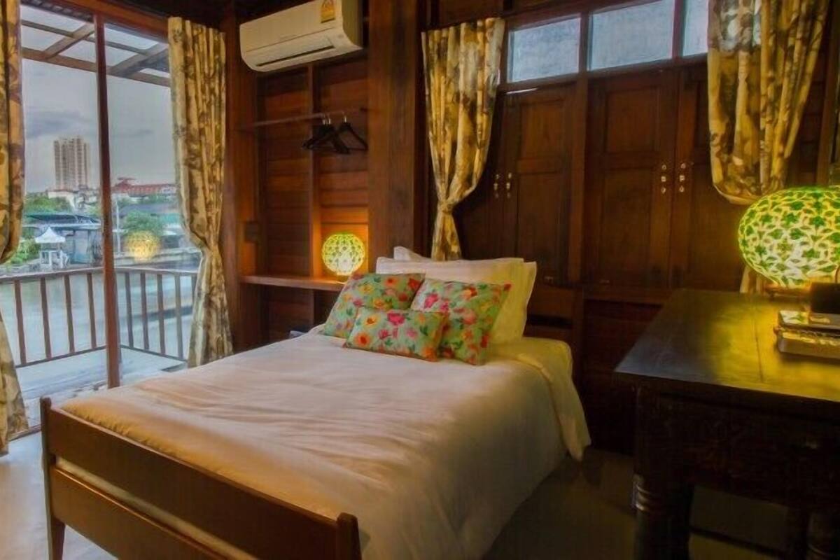 Een kamer met een bed, een bureau en uitzicht op een stadsgezicht door grote ramen.