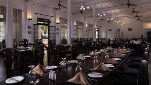 A large dining hall with multiple tables set for service, ceiling fans, and chandeliers. - Queen's Hotel (Kandy)