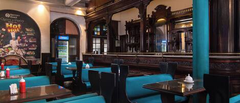 A restaurant with teal booths, wooden tables, and a Pepsi refrigerator.