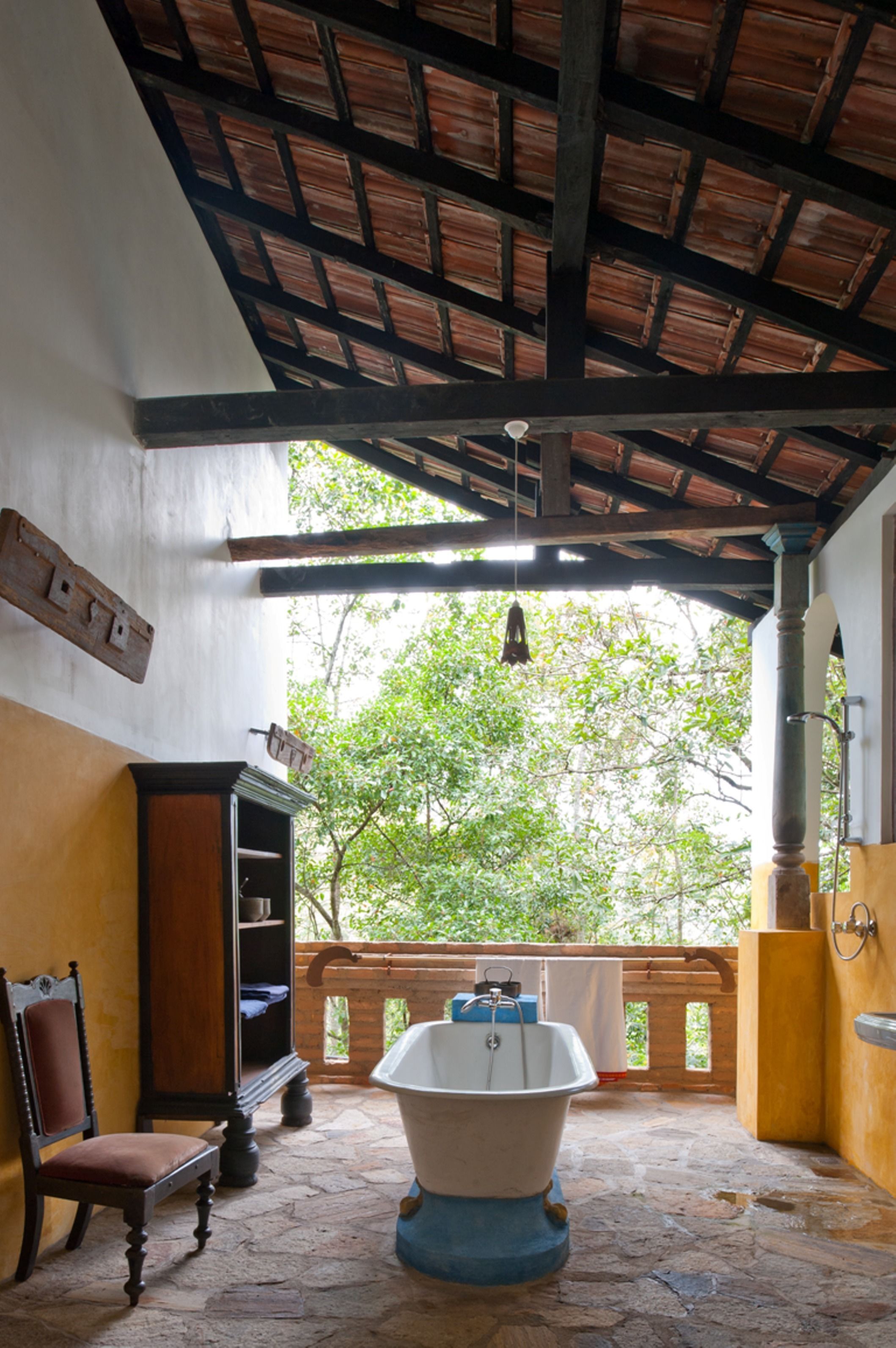 A bathroom with a bathtub, a wooden chair, and a shelf.