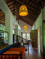 Amplo interior com teto alto, vigas de madeira e escadaria que dá acesso a pisos superiores.