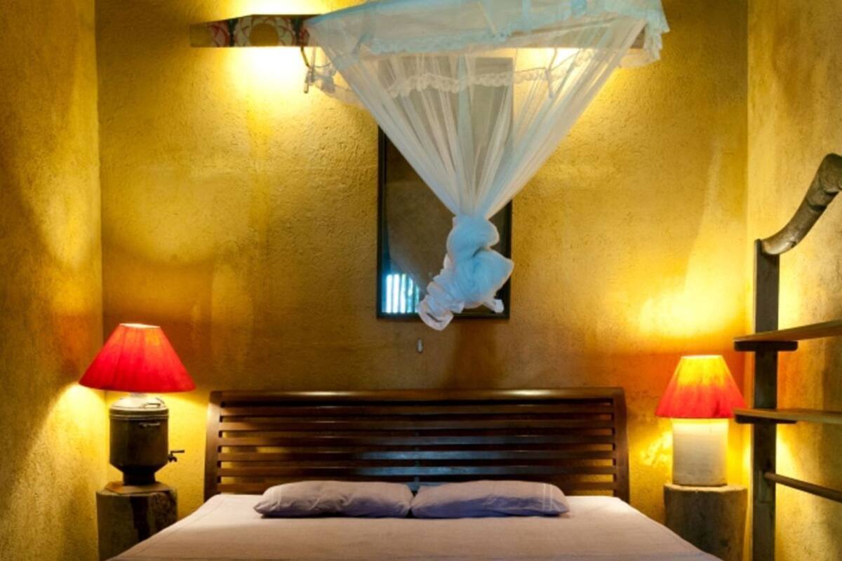 A bed with a canopy, two bedside lamps, and a wooden headboard.