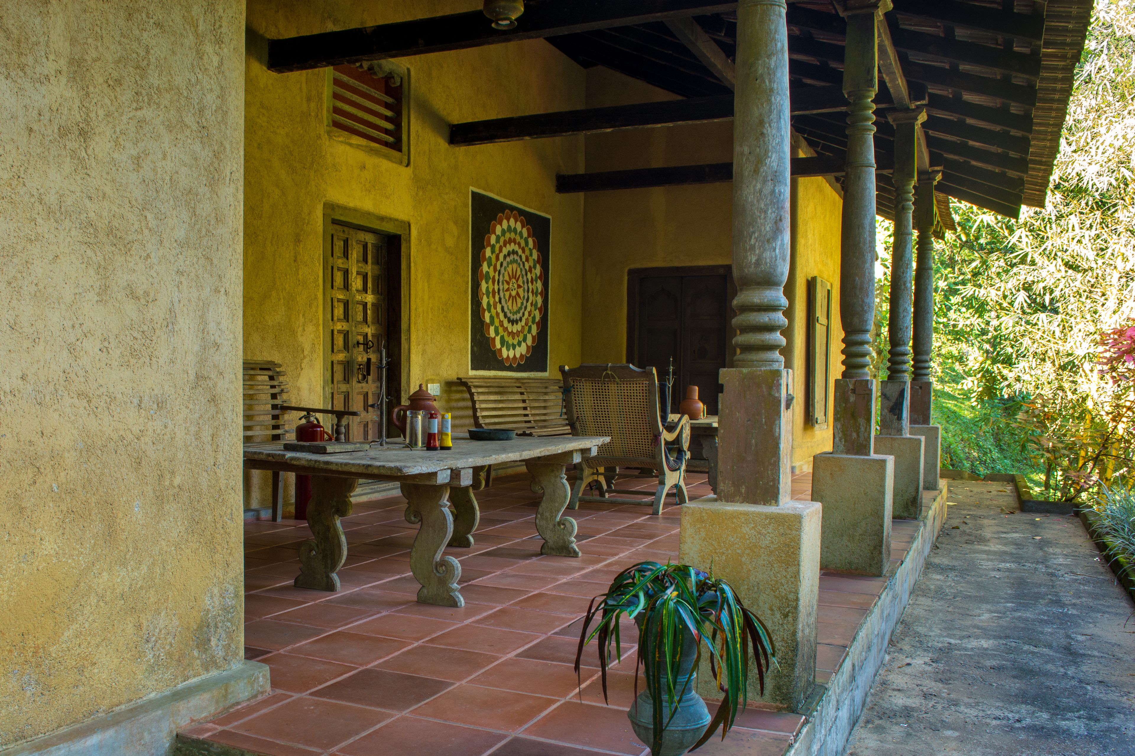 A covered patio area with a table, chairs, and a potted plant.