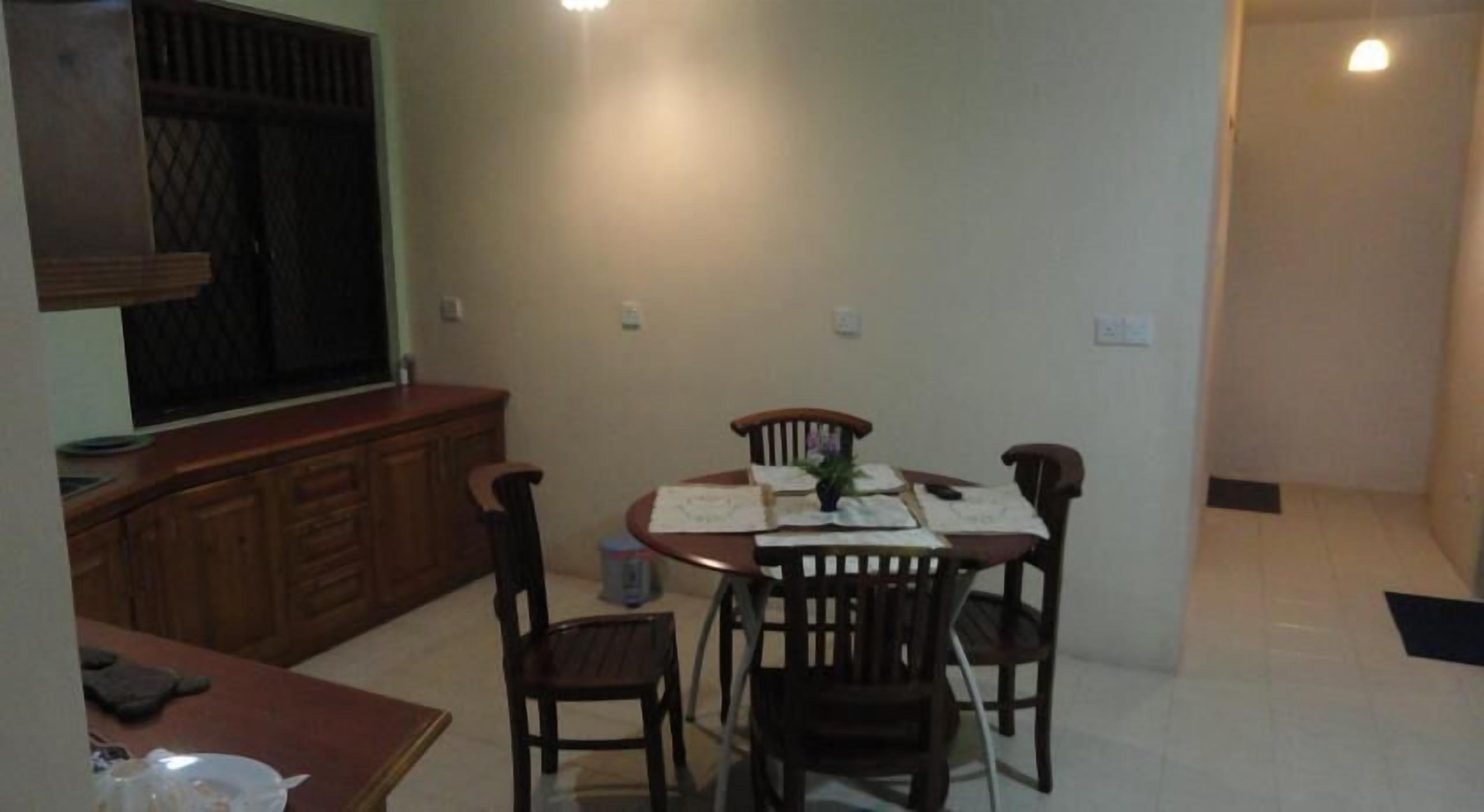 A dining area with a round table, four chairs, and a wooden cabinet.