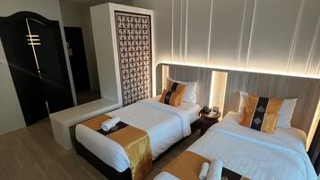 A hotel room with two beds, a desk, and a wardrobe.