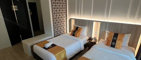 A hotel room with two beds, a desk, and a wardrobe.