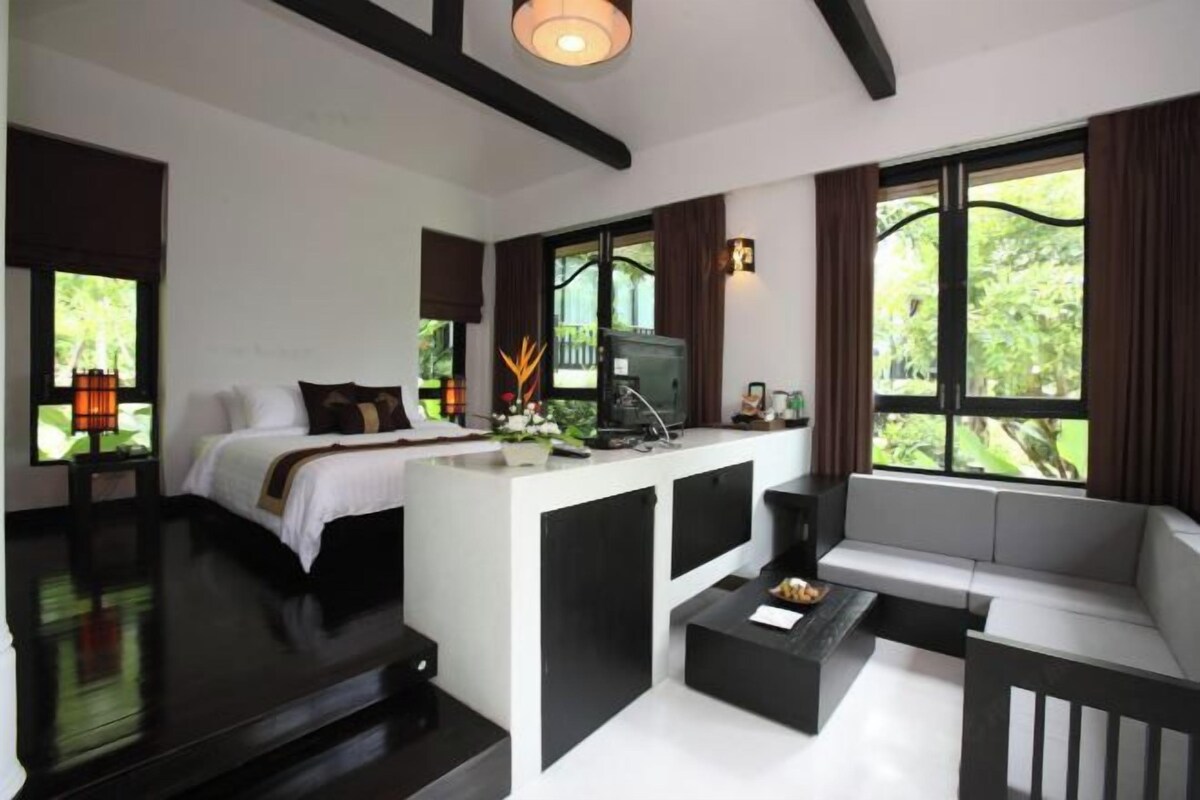 Una habitación de hotel moderna con una cama, un sofá, una mesa de centro y una televisión.