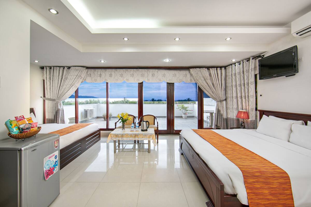A hotel room with a bed, a desk, a TV, and a view of the outdoors.