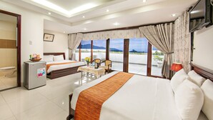 A hotel room with two beds, a refrigerator, a table with chairs, and a view of the outdoors. - Dreams Hotel Danang (Da Nang)