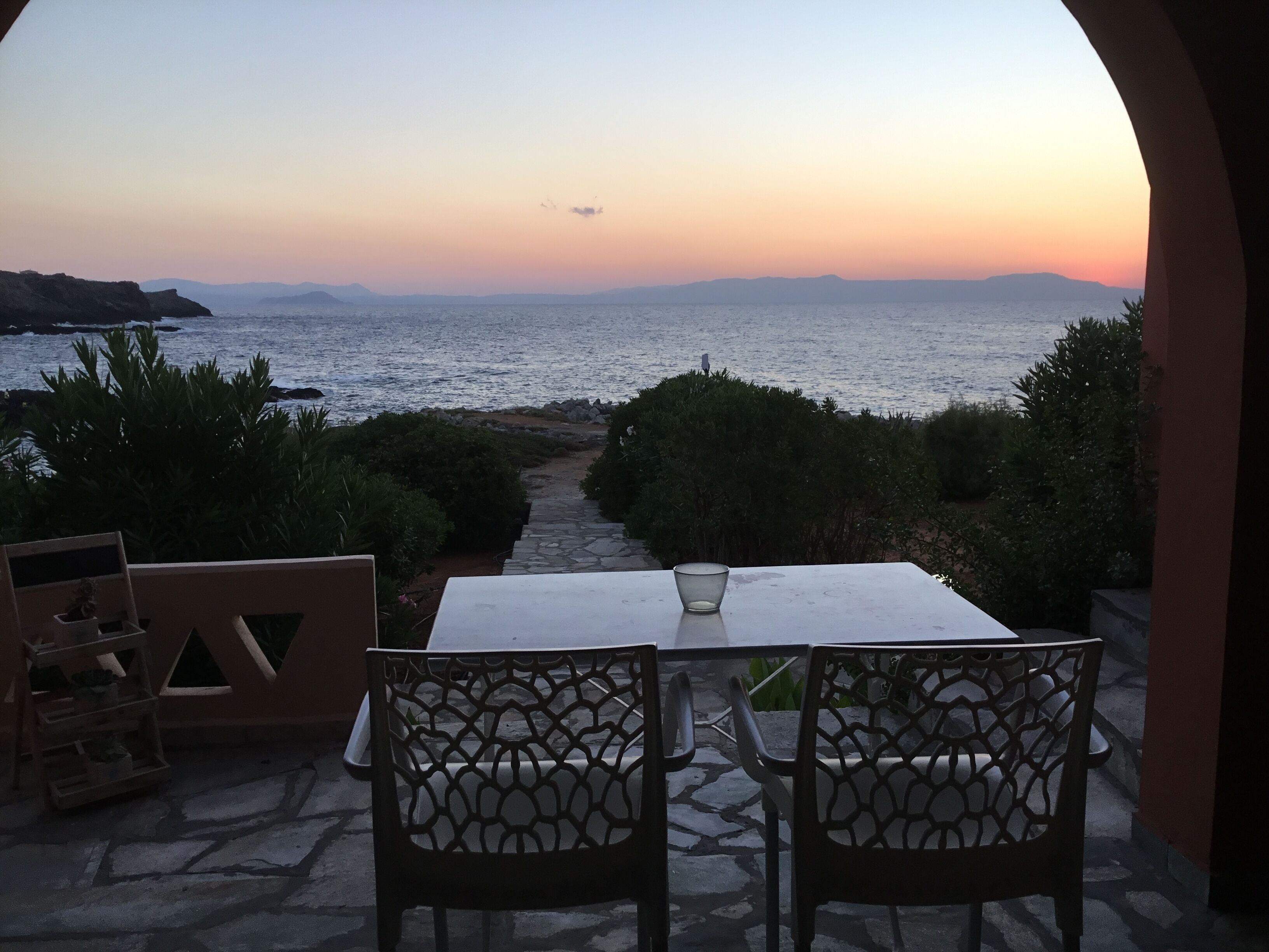 A table and chairs set up for dining with a view of the sea and distant mountains.