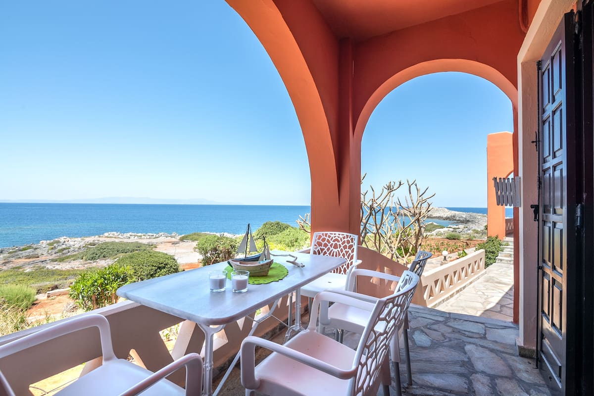 An outdoor patio with a table and chairs, overlooking a coastal landscape.