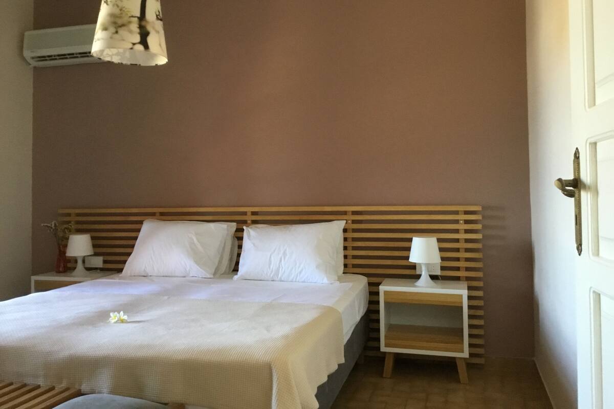 A bedroom with a wooden headboard, two bedside tables with lamps, and a bed with white linens.