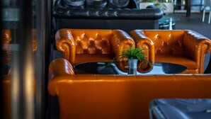 Un área de estar interior con sofás de cuero y una pequeña mesa, un separador de vidrio y vistas a un espacio exterior con vegetación.