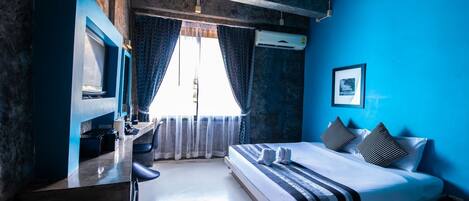 A bedroom with a bed, a desk, and an air conditioning unit.