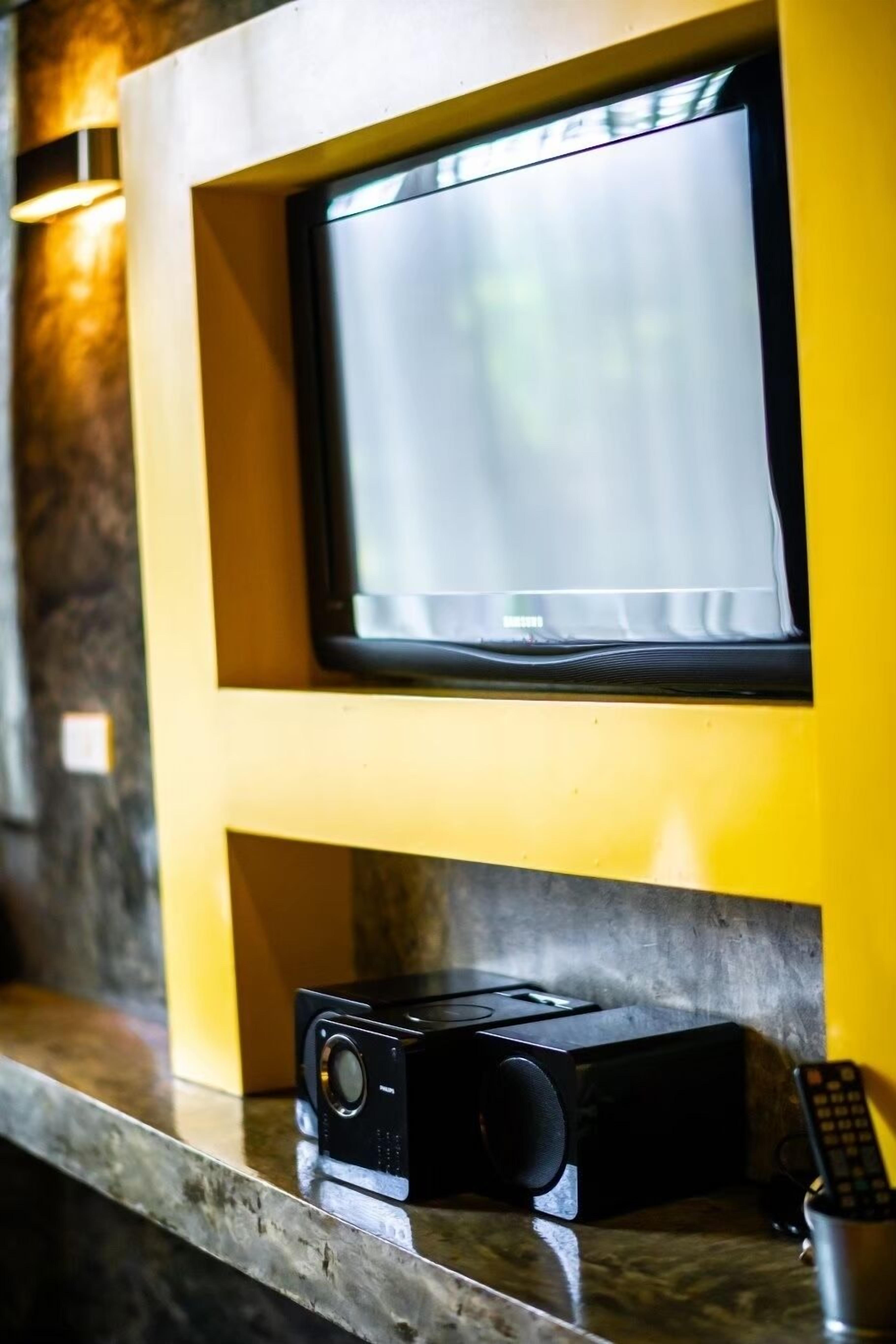 Un televisor montado en la pared con un control remoto sobre el mostrador.