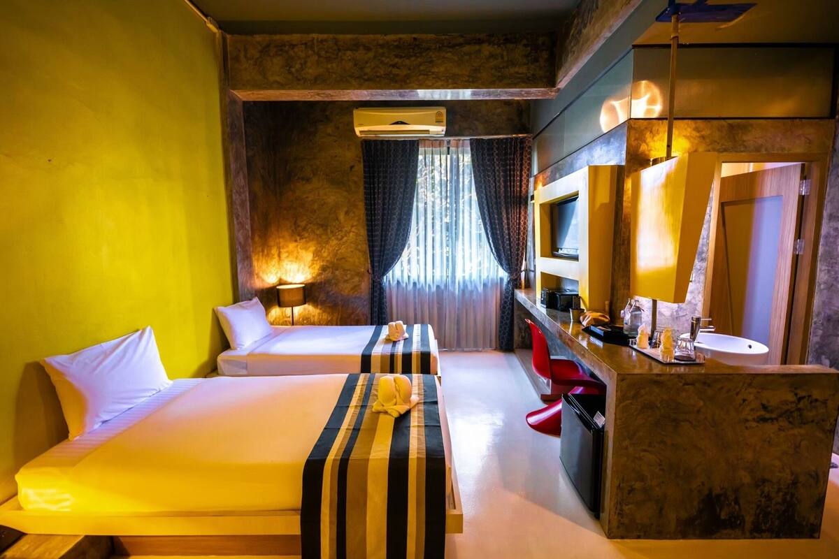 A hotel room with two beds, a desk, a TV, and a bathroom.