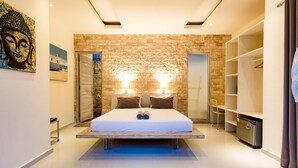 Une chambre moderne avec un mur en pierre, un lit avec deux oreillers, une table de chevet et une armoire intégrée.