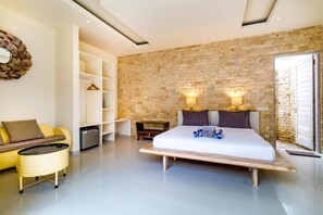 Een moderne slaapkamer met een groot bed, bedlampen, een houten nachtkastje, een bank en een inbouwkast.