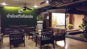 A restaurant interior with wooden furniture, a green wall with Thai text, and a ceiling fan. - Palm Sweet Resort (Chumphon)