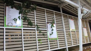 A wall with multiple menus and a fan. - Pueanjai Resort and Restuarant (Chumphon)