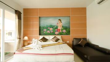 A hotel room with a large bed, a painting of a woman with flowers, a sofa, and a window with curtains.