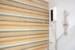 Una ducha con panel de control y cabezal de ducha de mano.