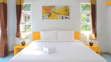 Habitación de hotel con una cama grande, dos mesitas de noche con lámparas, un cuadro en la pared y cortinas en las ventanas.