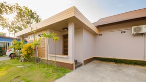 A modern building with a flat roof, a small porch, and a concrete driveway. - Pueanjai Resort and Restuarant (Chumphon)