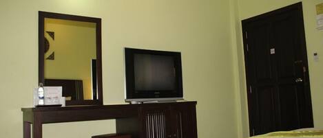Habitación de hotel con una cama, un televisor sobre un soporte de madera, un espejo y una puerta.