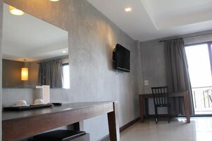 Una habitación de hotel moderna con un espejo grande, un televisor de pantalla plana en la pared, un escritorio de madera y una silla.