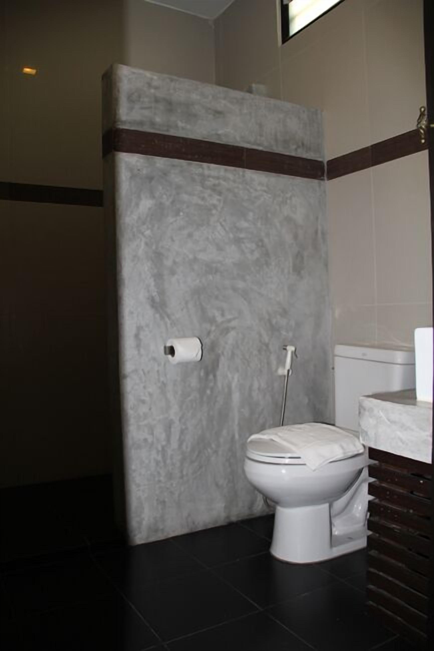 Un baño con pared de mármol, inodoro, bidé y toallero.