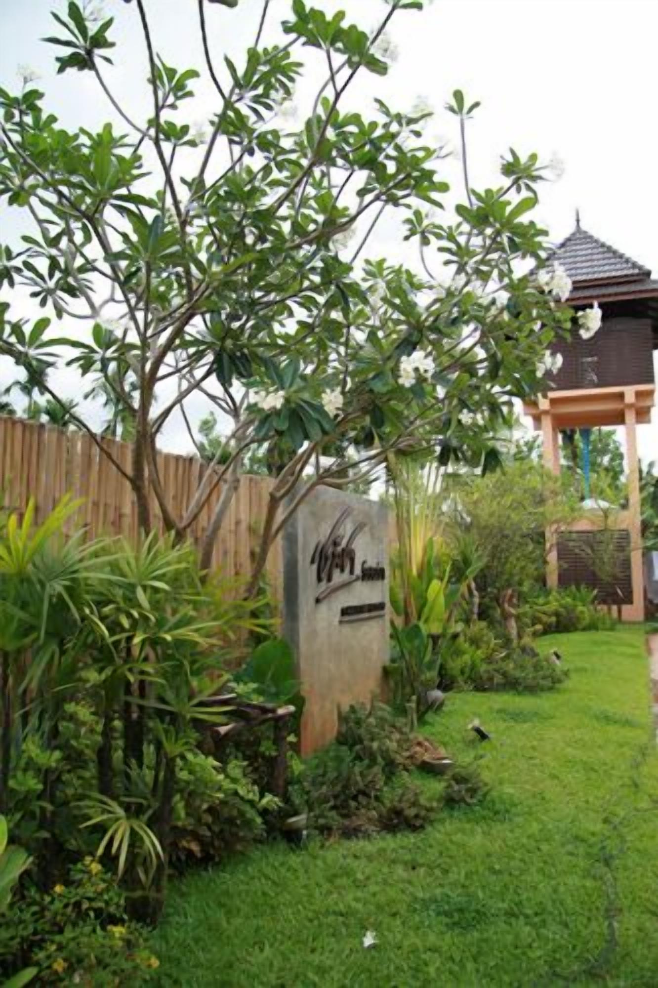 A garden with a wooden fence, a sign, and a gazebo.