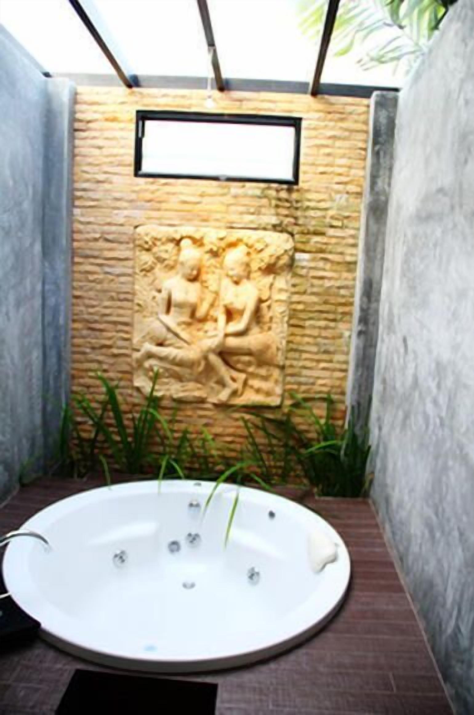 A spa area with a hot tub, stone wall, and a relief sculpture.