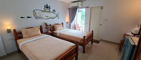 Habitación de hotel con dos camas de madera, un mural de peces en la pared, una lámpara de techo y una puerta corrediza de cristal al exterior.